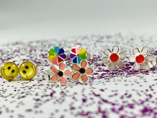 A variety of stylish ear studs in vibrant colors displayed on a white background.