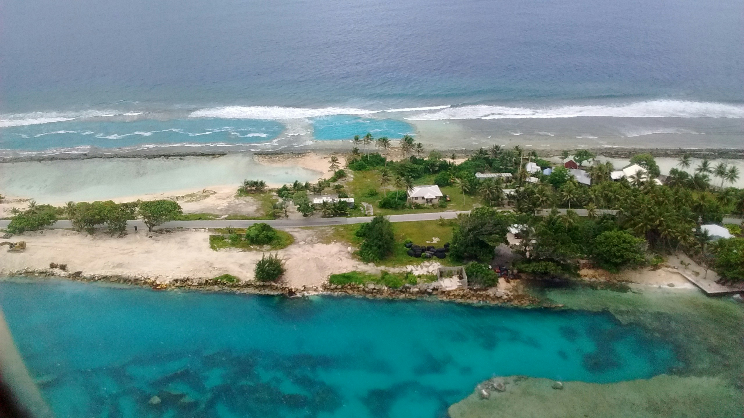 Aerial view of turquoise Caribbean waters with white sand beach and palm trees on a tropical island