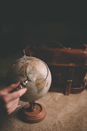 Hand holding a magnifying glass near a globe representing worldwide opportunities.
