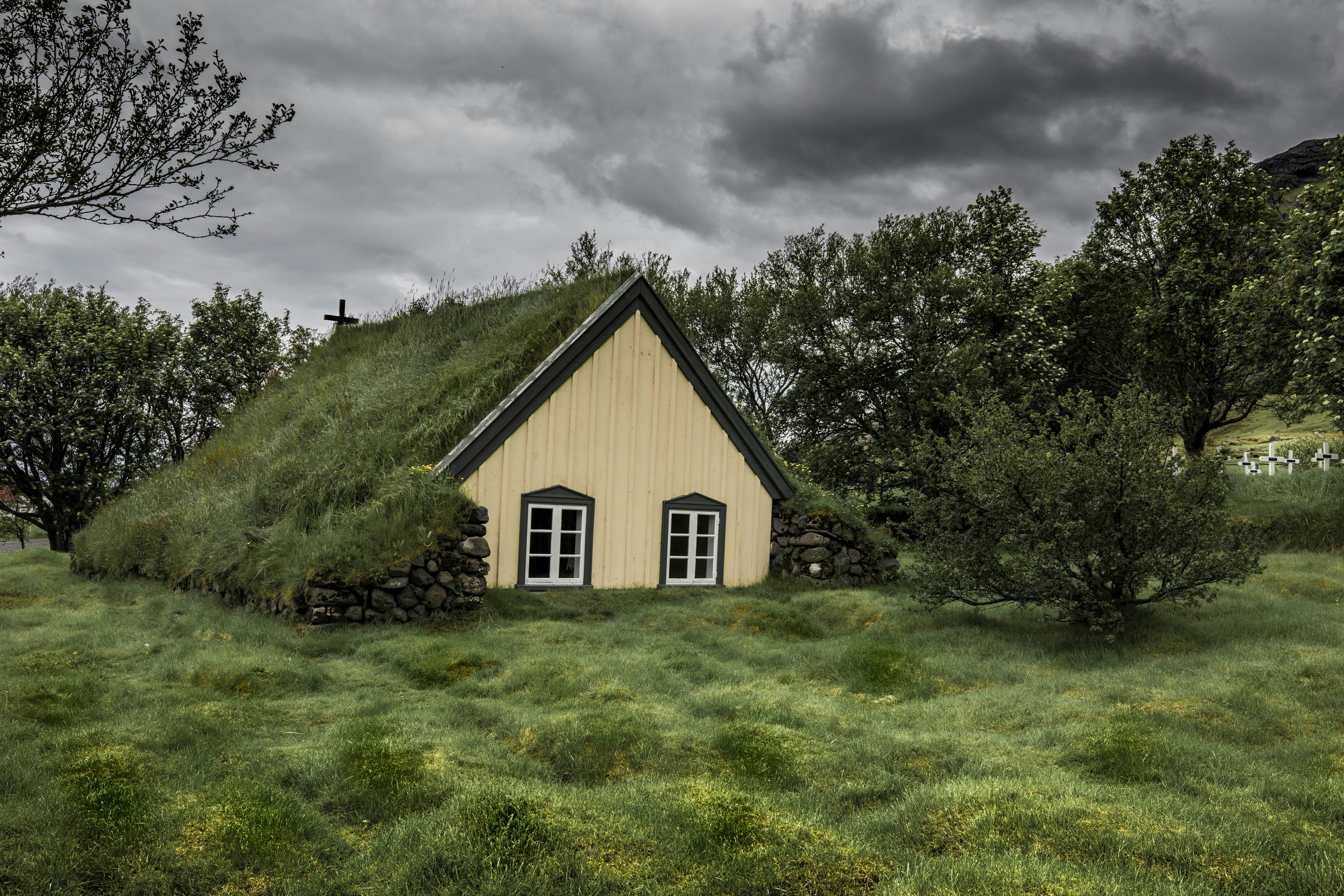 brown wooden house surrounded with green trees under gray clouds