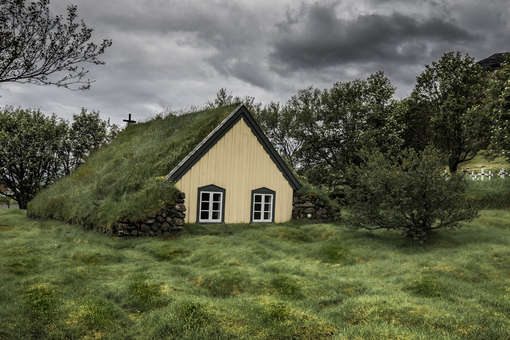 braunes Holzhaus, umgeben von grünen Bäumen unter grauen Wolken