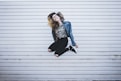 woman jumping in front of white concrete establishment