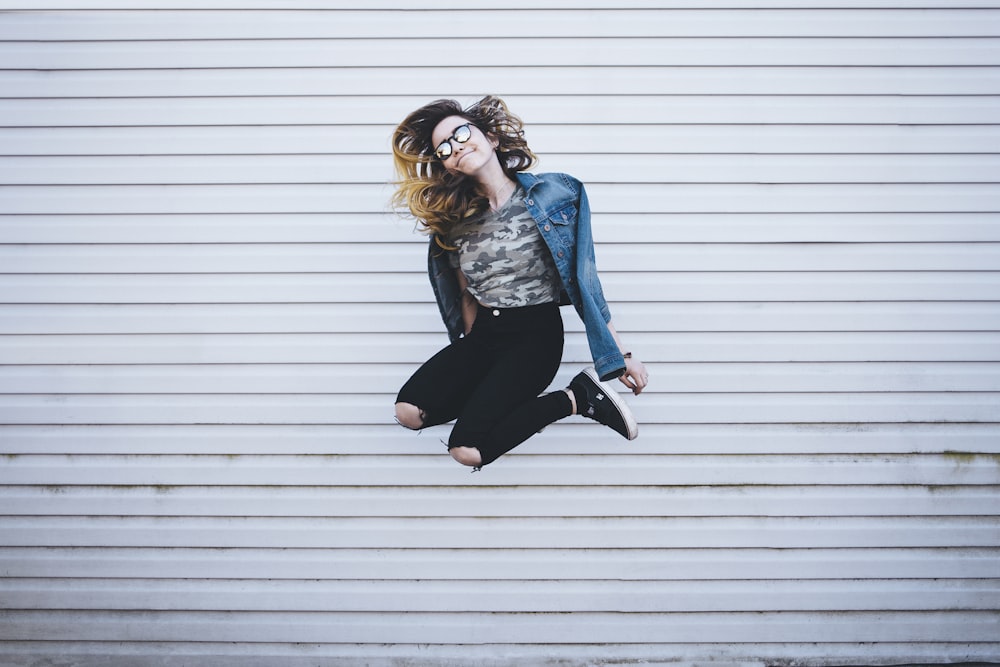 woman jumping in front of white concrete establishment