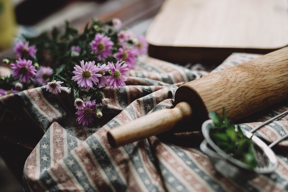 brown rolling pin near pink flowers