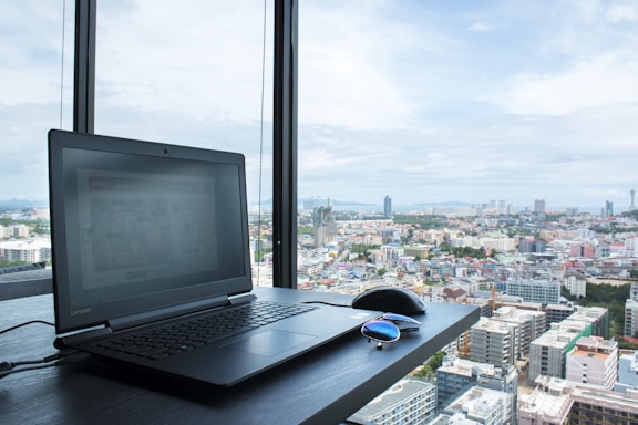 An open laptop showing the jdglobalsync sales platform interface with a city skyline in the background.