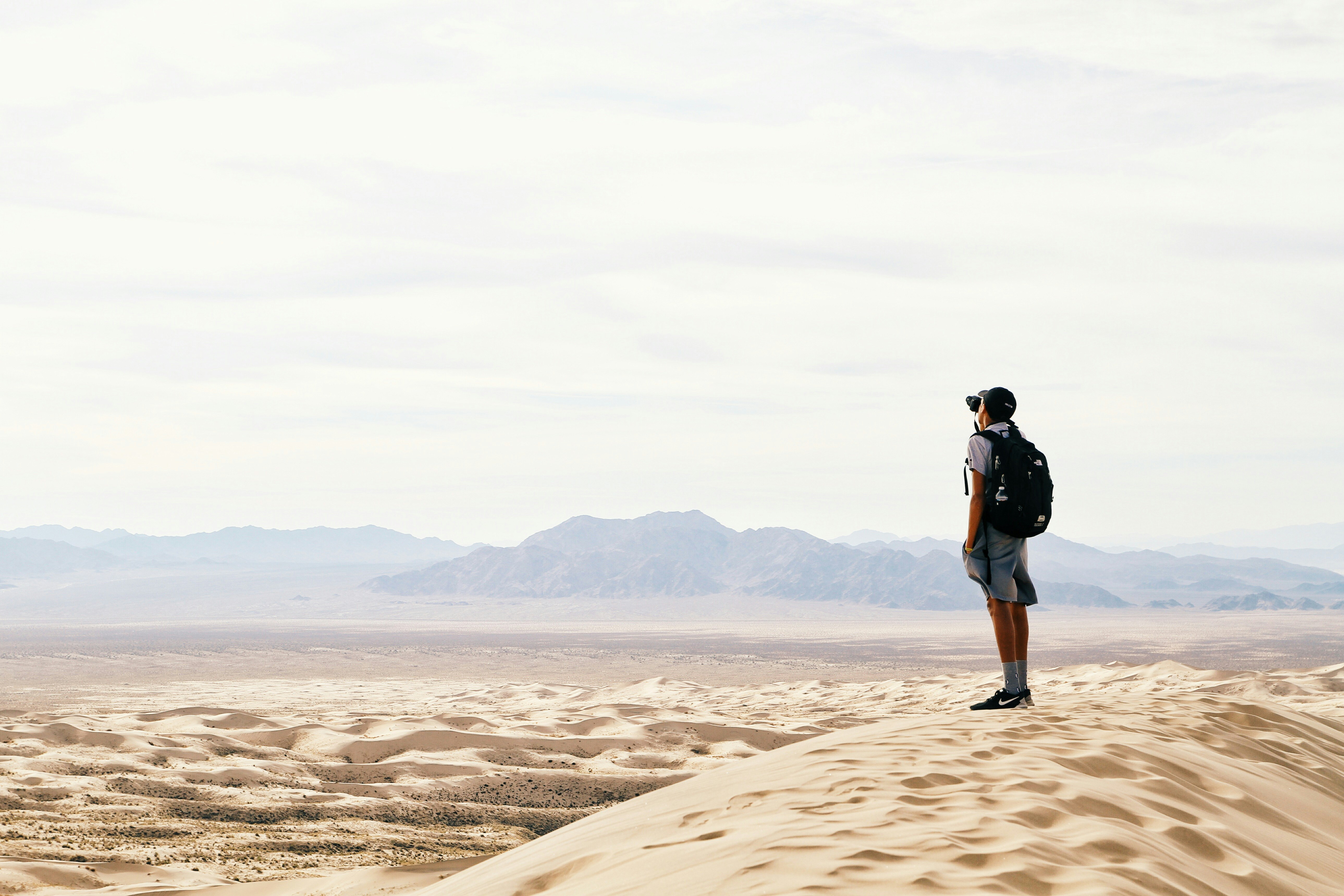 man standing and carrying backpack in desert land