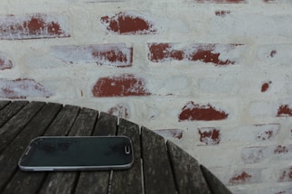 A rustic wooden table with a smartphone displaying a WhatsApp chat open, surrounded by country-style leather horse tack.