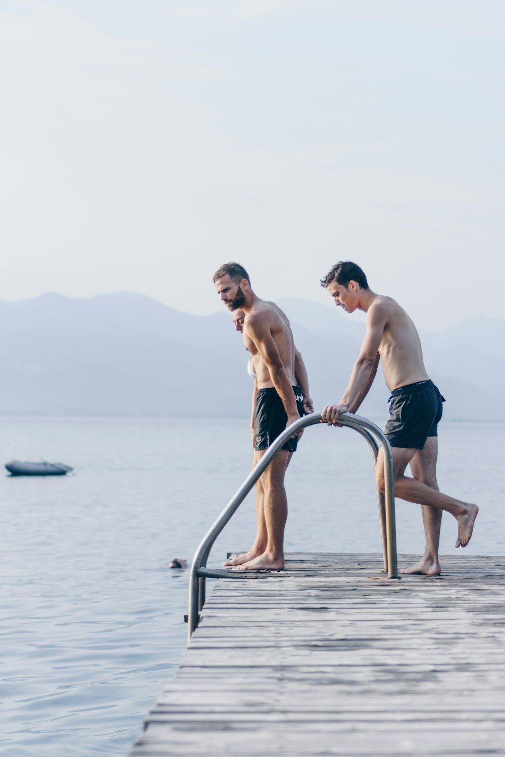 Zwei Männer stehen tagsüber auf dem braunen Dock in der Nähe eines Gewässers