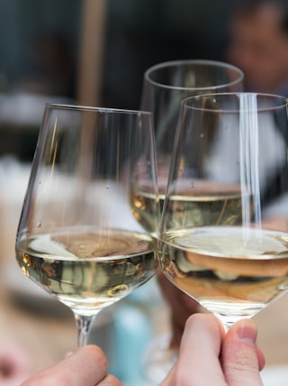 three people having a toast using three clear crystal wine glasses