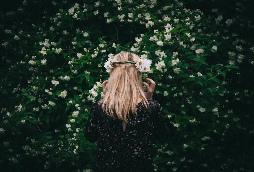 Selektive Fokusfotografie einer Frau, die vor weißblättrigen Blumen steht