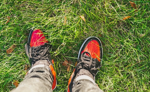 Bright rubber shoes displayed outdoors on a sunny day with green grass background