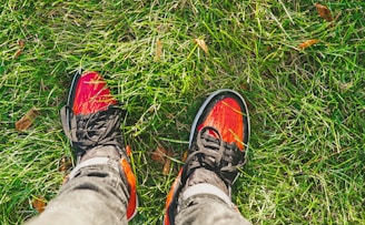 Bright rubber shoes displayed outdoors on a sunny day with green grass background
