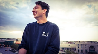 A candid portrait of a man smiling warmly against a backdrop of his favorite cityscape.