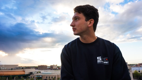 A thoughtful man gazing out over a city skyline, symbolizing ambition and reflection.