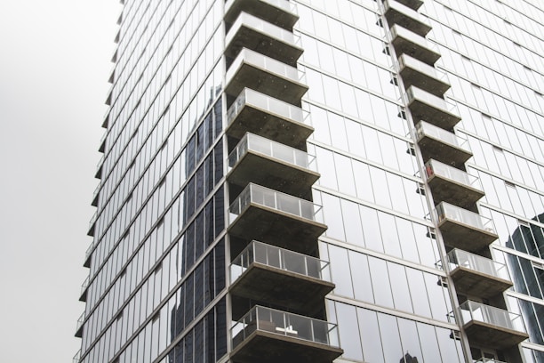 Modern downtown apartment building with large glass windows reflecting the city skyline.