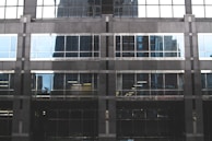 Close-up of a modern building window with thick bulletproof glass reflecting sunlight.