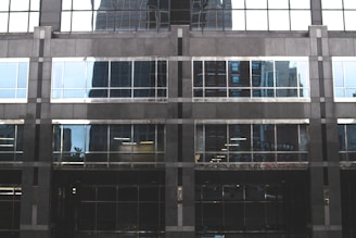 Close-up of a modern building window with thick bulletproof glass reflecting sunlight.