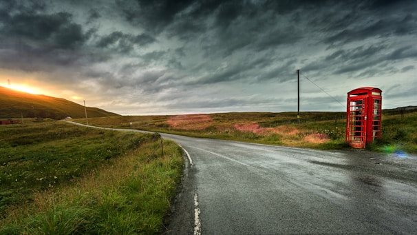 red telephone booth beside road