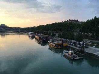 Sunset view over the river with rafting boats docked and people chatting by the shore.