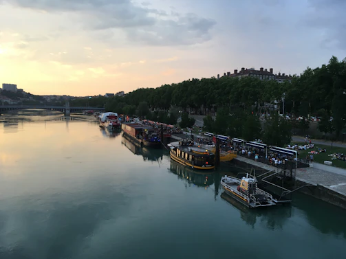 Sunset view over the river with rafting boats docked and people chatting by the shore.