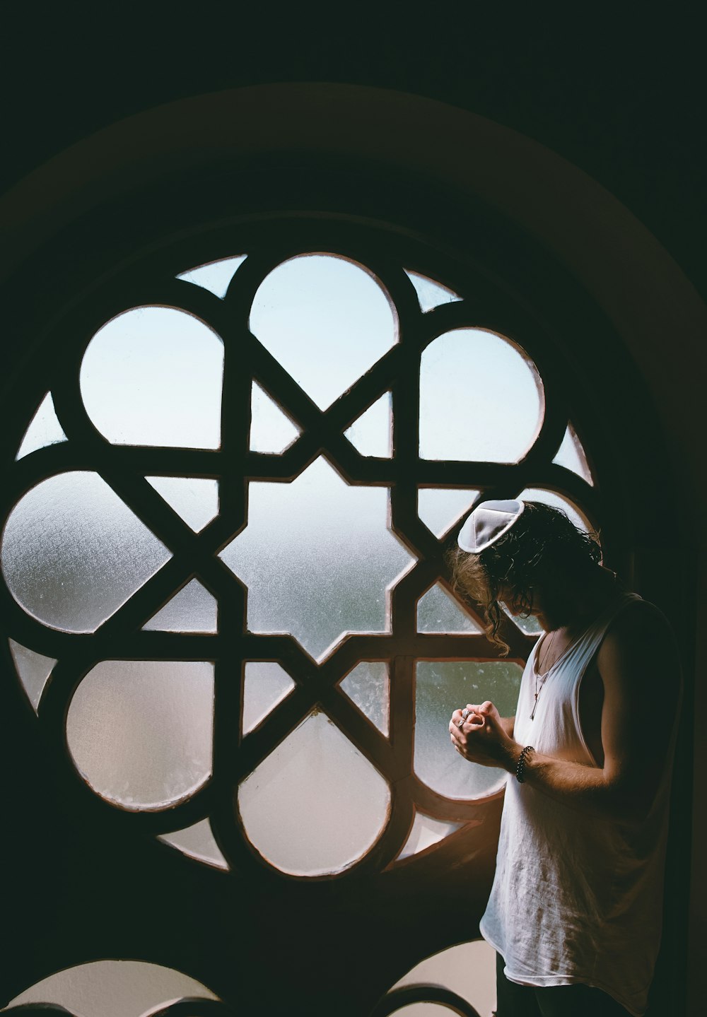 man in white tank top beside glass window