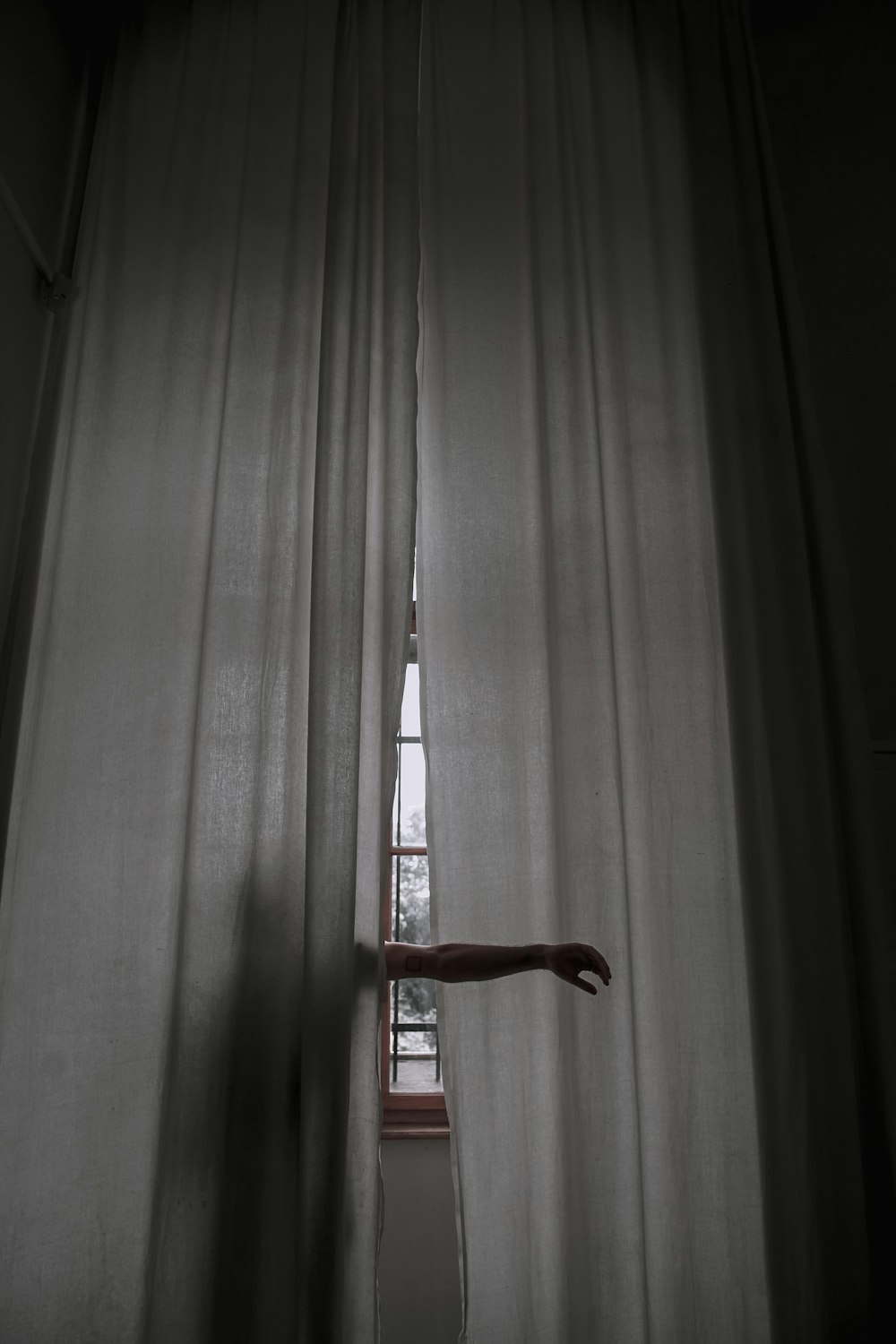 person standing beside the curtain and rising their arms