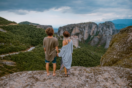 man and woman standing on the cliff in Meteora Greece