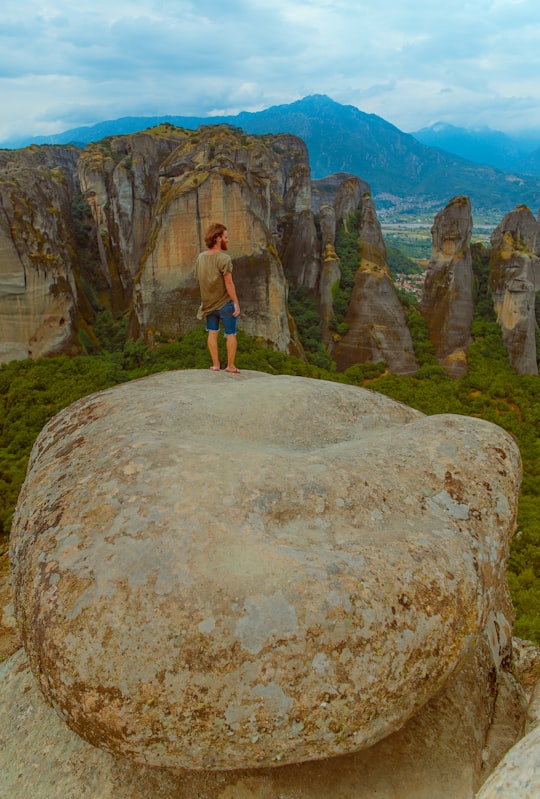 person standing on rock during daytime in Meteora Greece