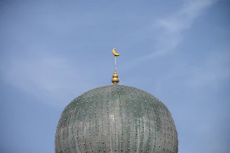 Close-up of Masjid Nabawi’s green dome under a clear blue sky.