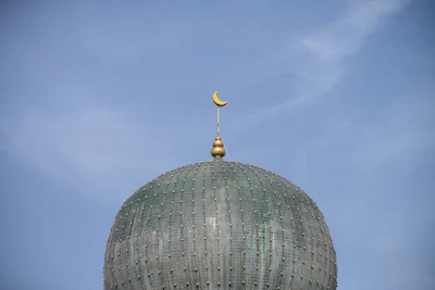 Close-up of Masjid Nabawi’s green dome under a clear blue sky.