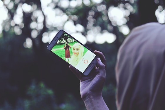 A person taking a photo with a smartphone outdoors.