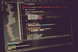 A computer screen displaying lines of code in a development environment. The code includes PHP syntax with functions, variables, and comments. The background is dark, and there are several open tabs with file names on the side.