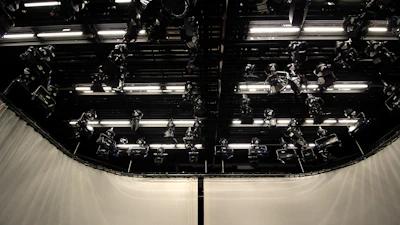 Wide shot of a spacious audiovisual studio with a seamless white cyclorama wall and professional lighting setup.