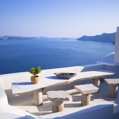 bench and dining table near body of water under calm sky