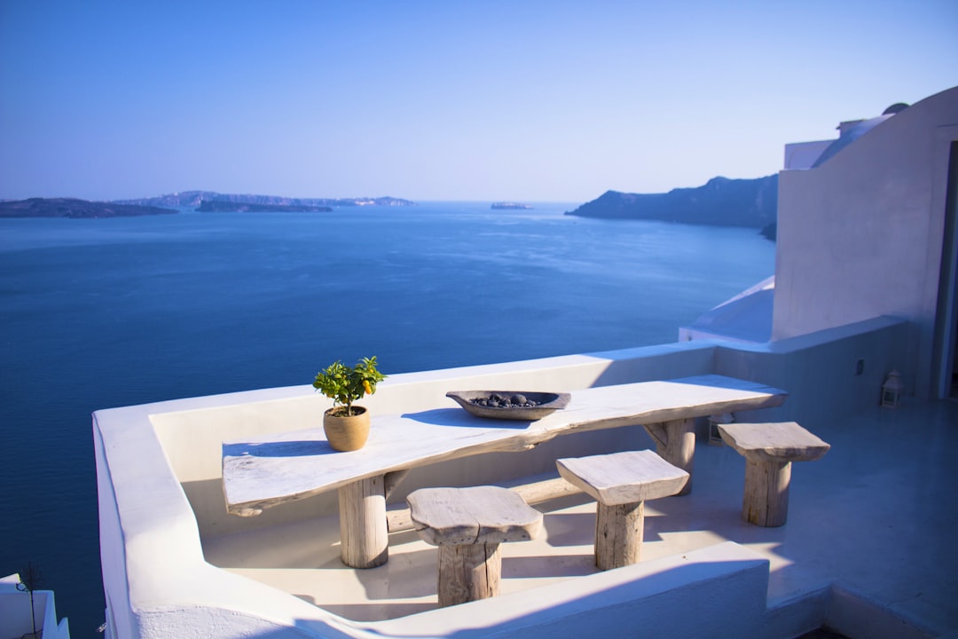 bench and dining table near body of water under calm sky