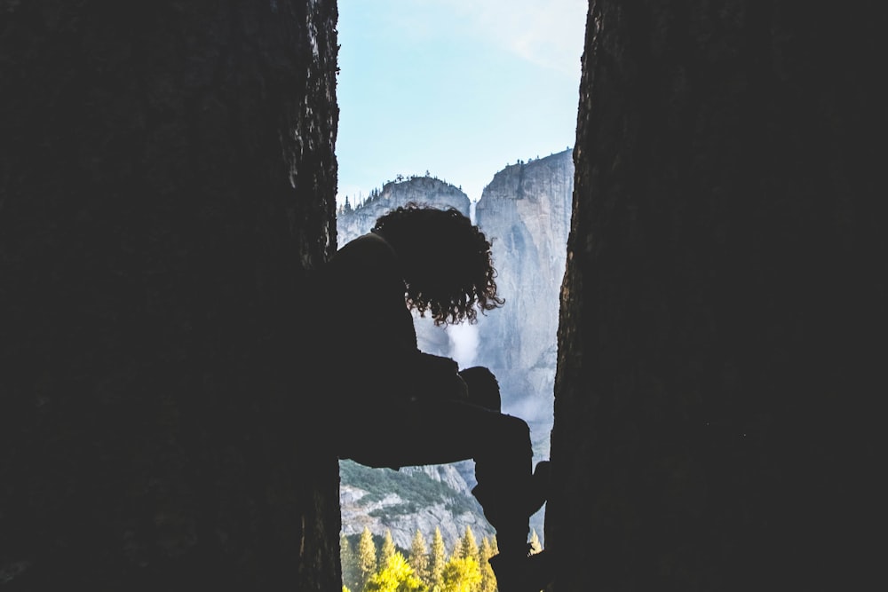 person between rock formation near falls during daytime