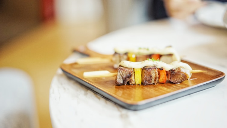A vibrant platter of assorted grilled meats and vegetables, beautifully arranged on a rustic wooden table.