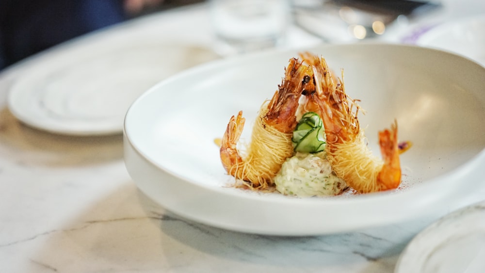 Photographie en gros plan de crevettes cuites sur une assiette ronde en céramique blanche