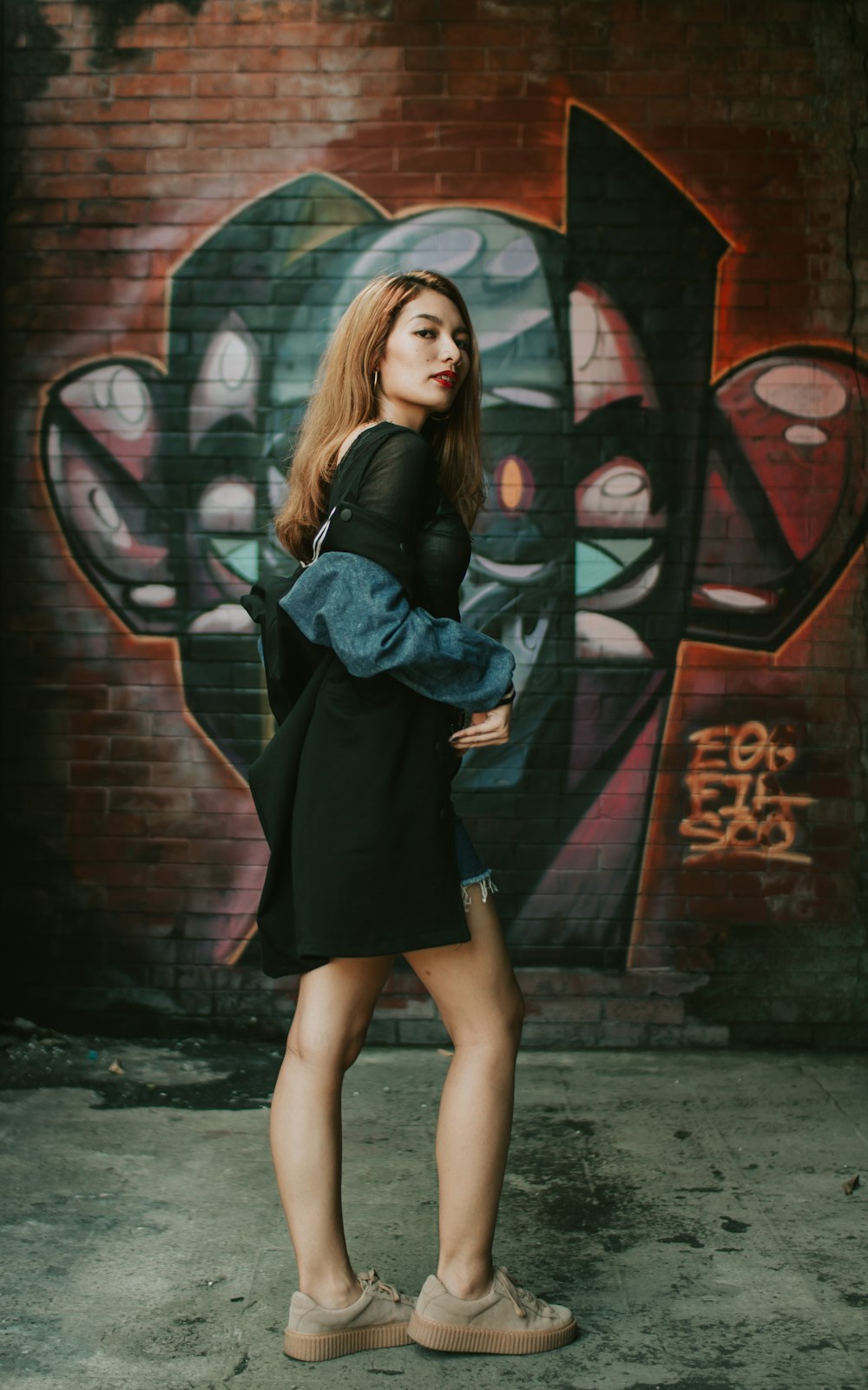 woman standing near wall with graffiti print during daytime