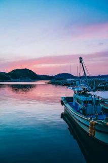 A serene boat docked at sunset in Paraty, with lush green hills in the background.