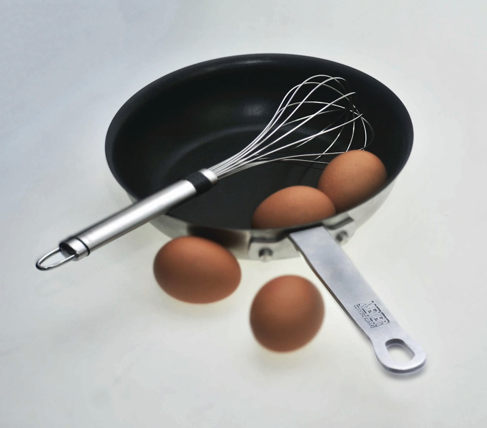 whisk on saucepan with organic eggs