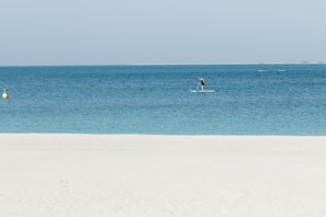 Family snorkeling in crystal-clear waters with paddle boards nearby.