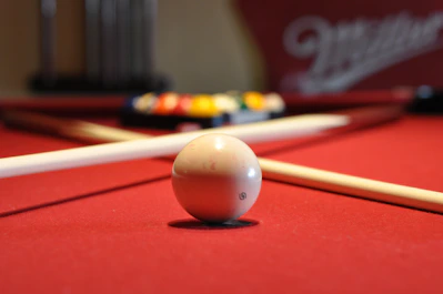 A close-up photo of a sleek billiard cue resting on a green felt table.