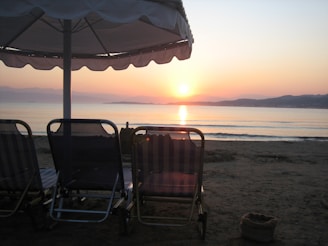 A serene beach at sunset with a comfortable lounge chair and a suitcase nearby, symbolizing a perfect vacation.