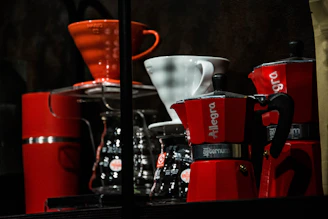 A collection of coffee mugs, grinders, and brewing tools arranged neatly on a wooden shelf.