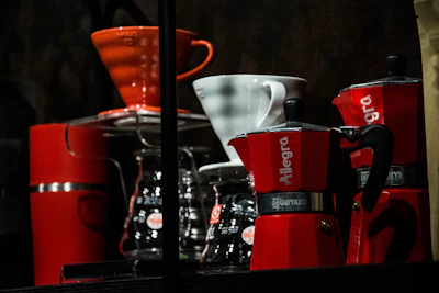 A collection of coffee mugs, grinders, and brewing tools arranged neatly on a wooden shelf.