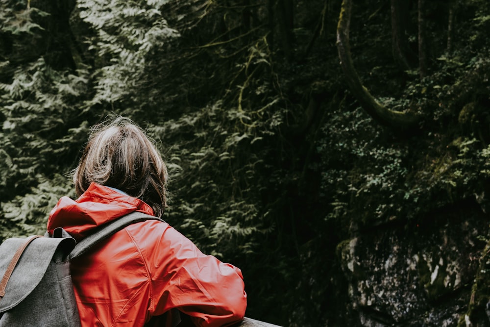 ragazza che si appoggia alla ringhiera di fronte alla foresta