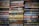 Stacks of paperback books arranged closely together, with a variety of titles and authors visible on the spines. The colors of the book covers range from muted tones to bright hues, creating a mosaic of literary works.