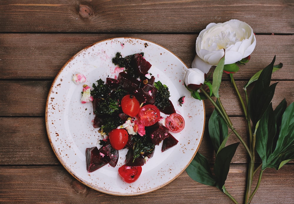 vegetables on dish beside white peony flower