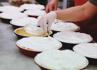 person wearing white latex gloves putting cream on bowls